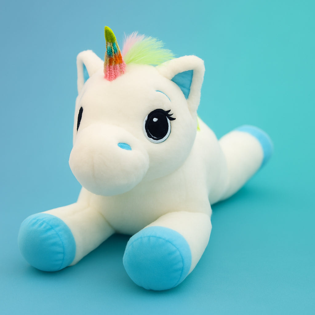 Plush unicorn toy with a rainbow horn on a light blue background